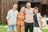 Smiling family of four posing outdoors, capturing love and togetherness.
